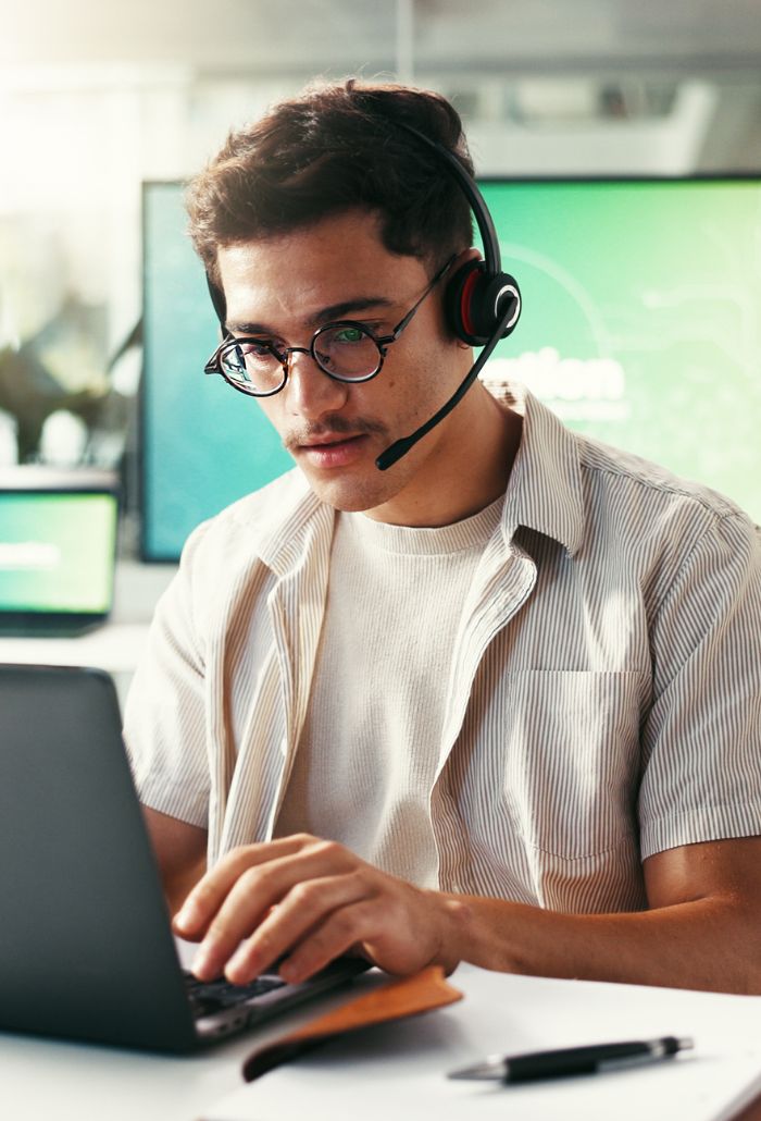 Mitarbeiter mit Headset arbeitet an einem Laptop im Büro – Symbolbild für Pentesting und IT-Sicherheitsprüfungen.