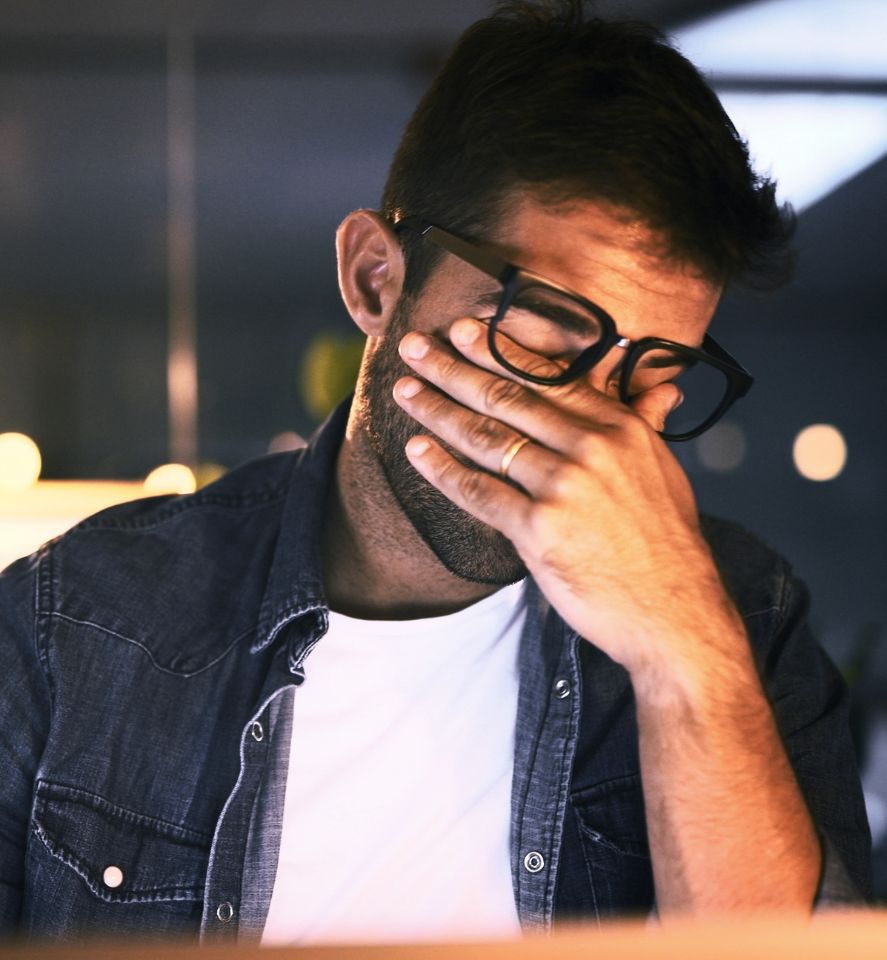 Ein erschöpfter Mitarbeiter sitzt am Computer und symbolisiert die Auswirkungen von Social-Engineering-Angriffen wie ClickFix und Cyberangriffen auf Unternehmen.