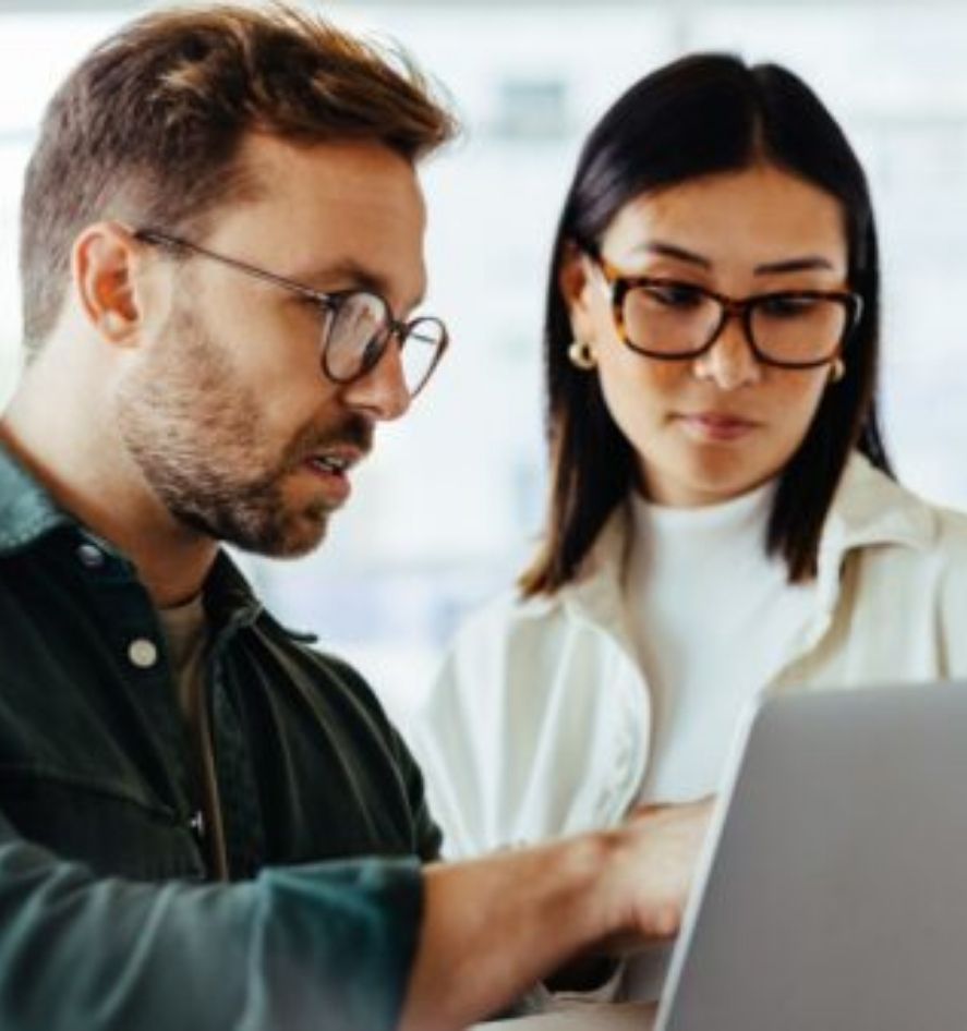 Zwei Mitarbeitende setzen NIS-2-Anforderungen und Compliance-Maßnahmen am Laptop effizient um.